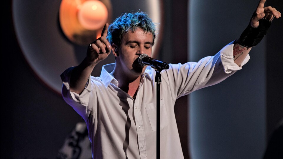 Les Louanges chante les bras en l'air.