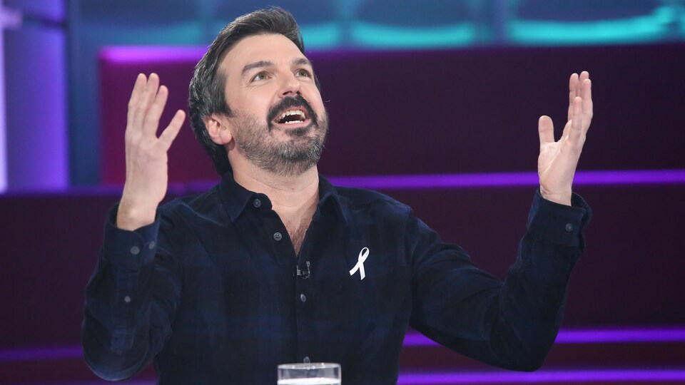 Damien Robitaille est à la table des invités de Tout le monde en parle. Il lève les bras et le visage vers le ciel.
