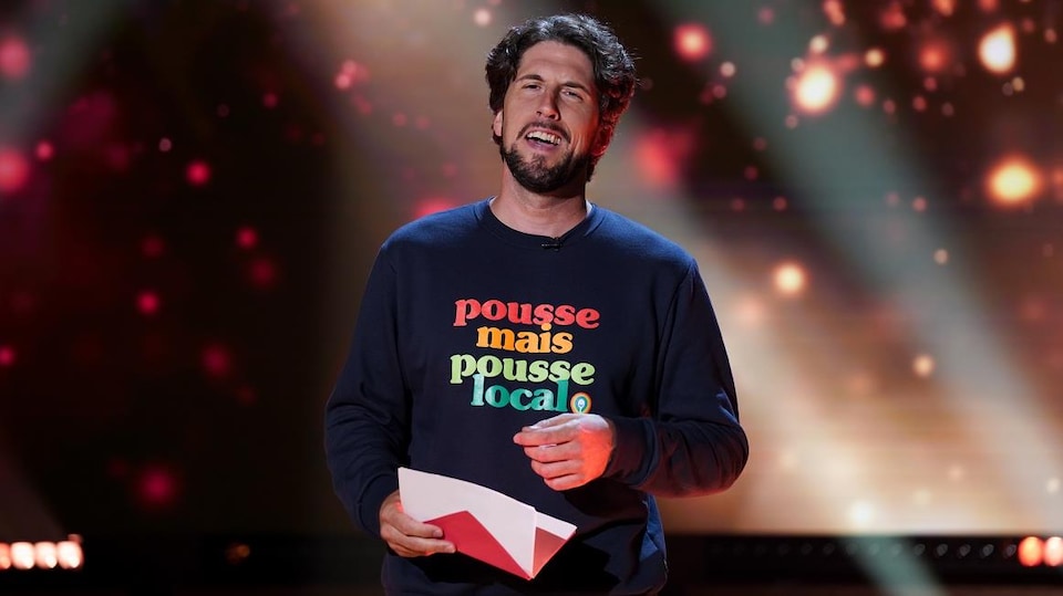 Un homme qui porte un chandail qui affiche le slogan suivant : Pousse, mais pousse local.