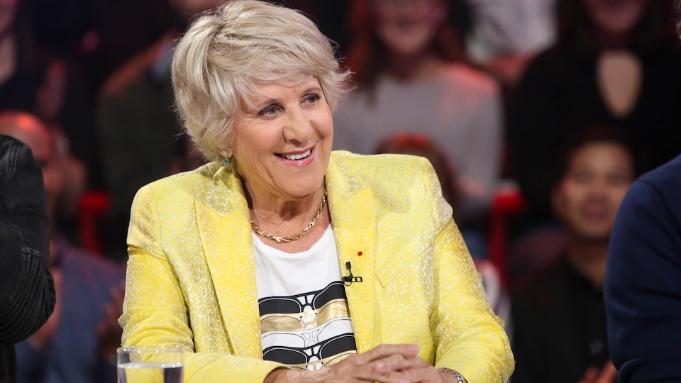 Elle porte un veston jaune.