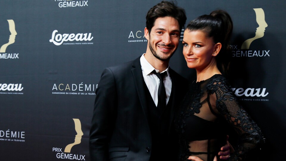 A man and woman side by side at a red carpet event posing for the cameras. 