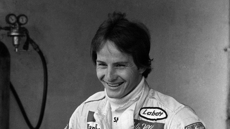 Portrait noir et blanc de Gilles Villeneuve souriant.