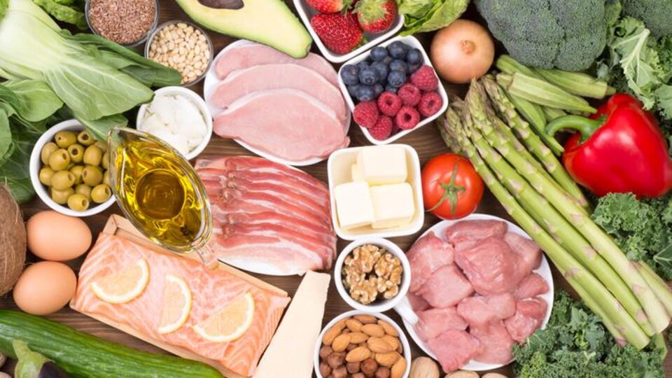 Plusieurs aliments, tels que du poisson et de la viande rouge, sont disposés sur une table en bois.