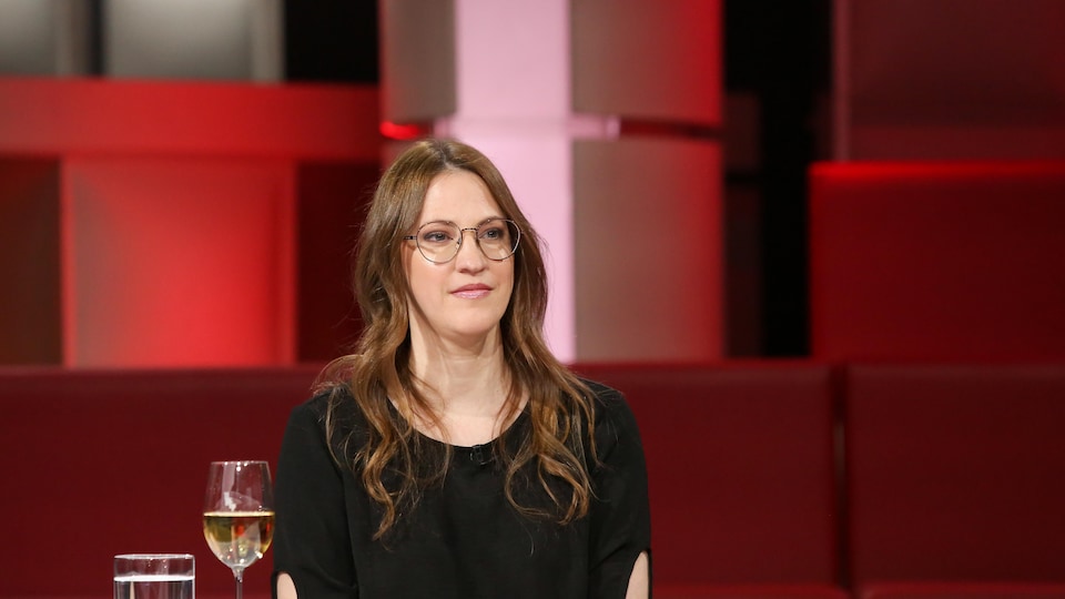 The woman was sitting in the vacant television studio behind him.  He was looking at the animator we couldn’t see.