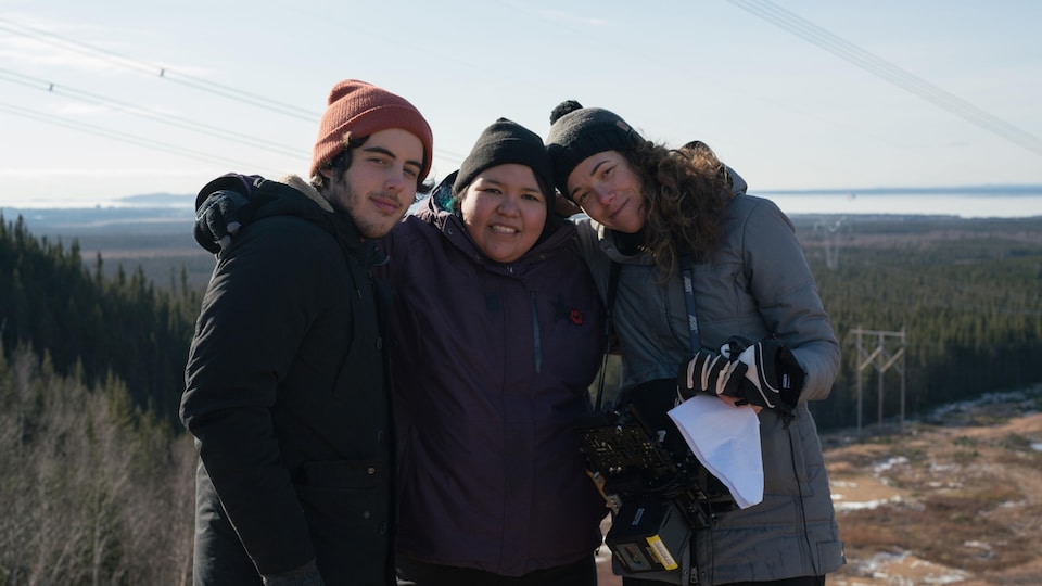 Un jeune homme (Etienne Galloy) et deux femmes (Sharon Fontaine-Ishpatao et Myriam Verreault), côte à côte, en extérieur.