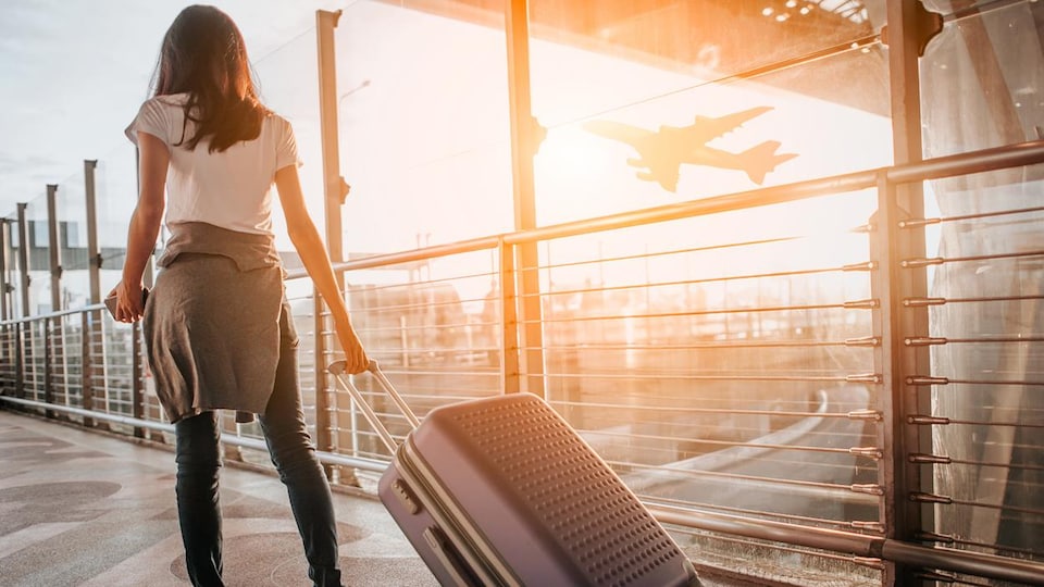 Une femme qui traîne sa valise à l'aéroport.