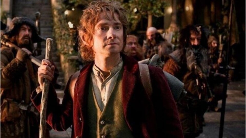 Un hobbit tenant un bâton de marche, devant d'autres créatures prêtes à aller marcher.