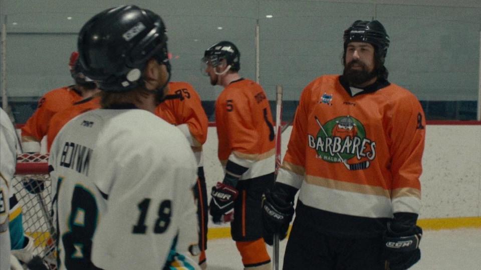 Un joueur de hockey (Philippe-Audrey Larrue St-Jacques) avec le chandail orange des Barbares de la Malbaie, sur la glace.
