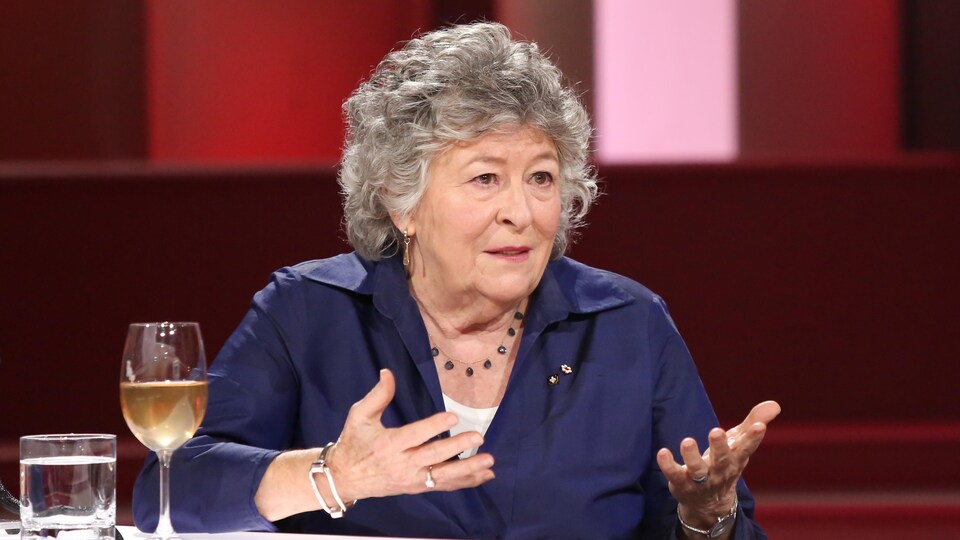 Louise Arbour est à la table des invités. Elle porte un chemisier violet.