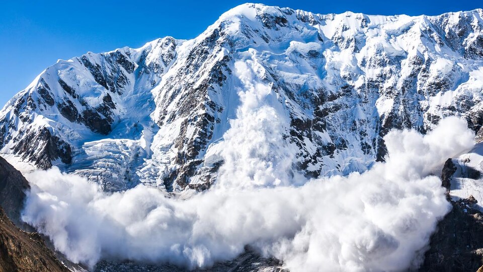 Une montage enneigée où se produit une avalanche.
