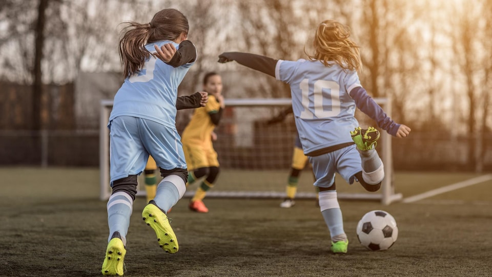 Deux jeunes filles s'apprêtent à marquer un but au soccer. 