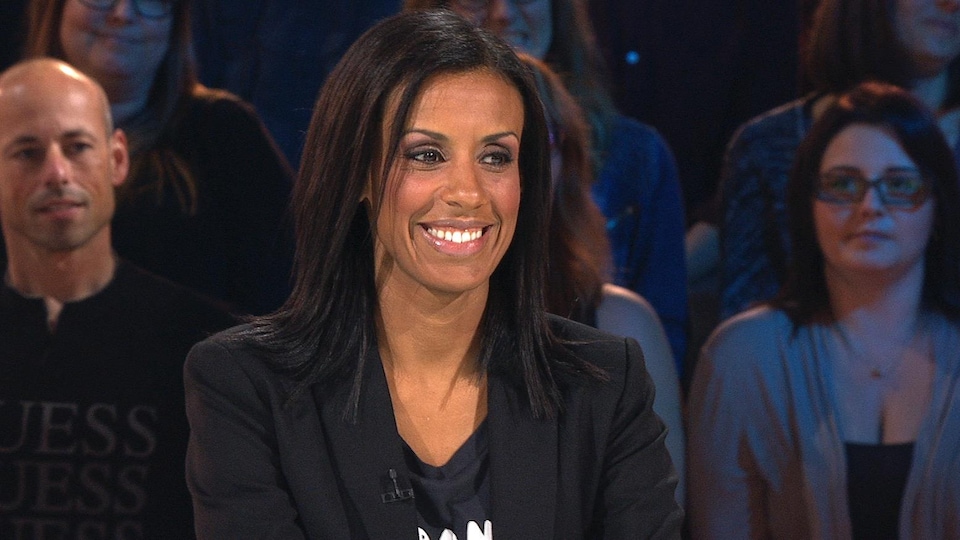 A woman smiles at a TV set.