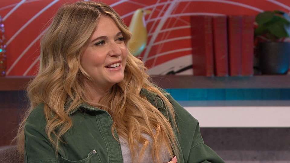 A woman with blond hair wearing a green jacket.