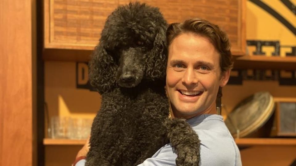 Sébastien Kfoury tient son caniche noir dans ses bras.