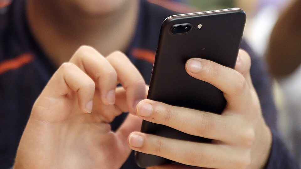 Une personne compose un numéro sur son cellulaire.