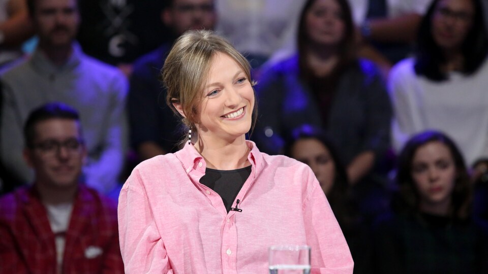 Catherine Dorion, souriante, est assise à la table des invités d'un plateau de télévision