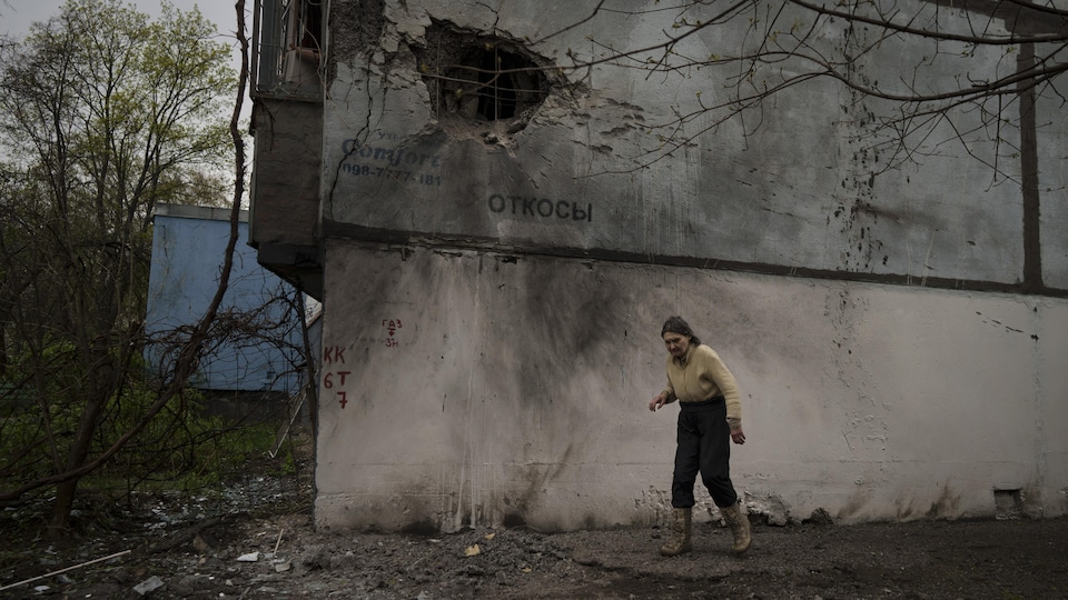 Une femme marche à côté d'un bâtiment endommagé après un bombardement russe à Kharkiv, en Ukraine, le mardi 19 avril 2022. 