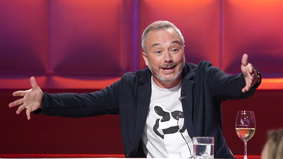 Un homme qui parle en ouvrant les bras.
