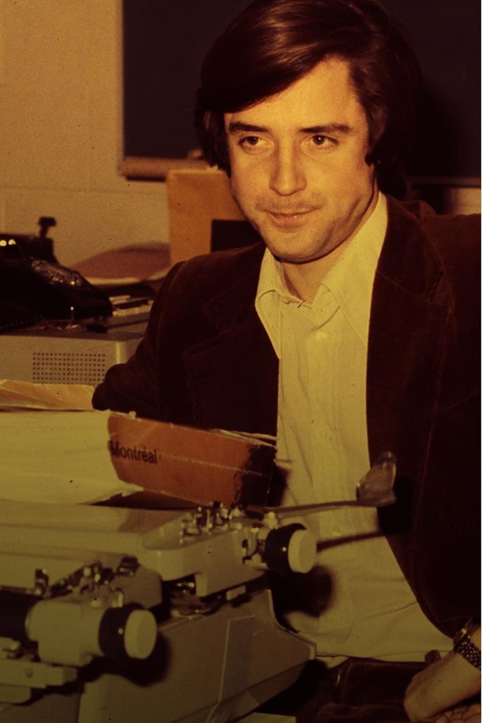 Le journaliste Charles Tisseyre est assis derrière une machine à écrire, dans la salle des nouvelles.