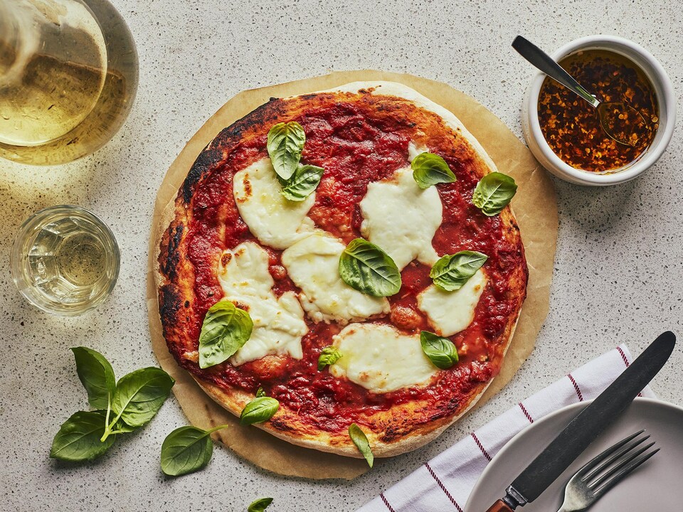 Une pizza Margherita est posée sur un papier parchemin rond.