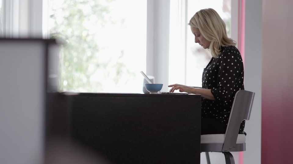 Une femme est assise devant son ordinateur et écrit un texte.