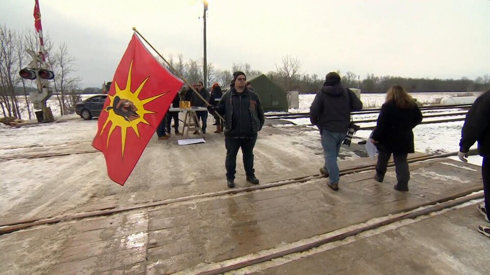Un homme tient un drapeau des Premières Nations Mohawk.
