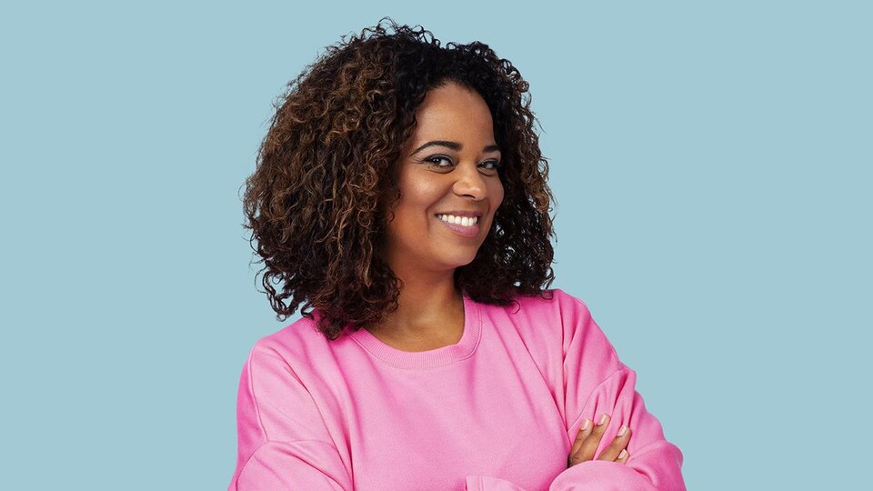 Elle sourit et porte un long sweat rose