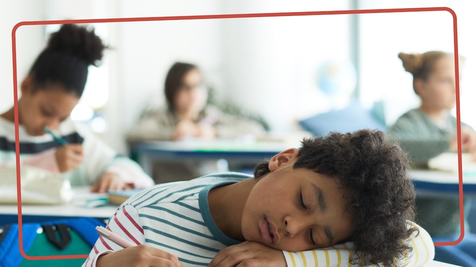 Un enfant qui dort sur son bureau en classe. 