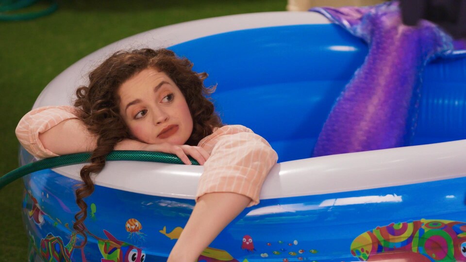 La jeune femme-sirène est dans une allongée dans une petite piscine.