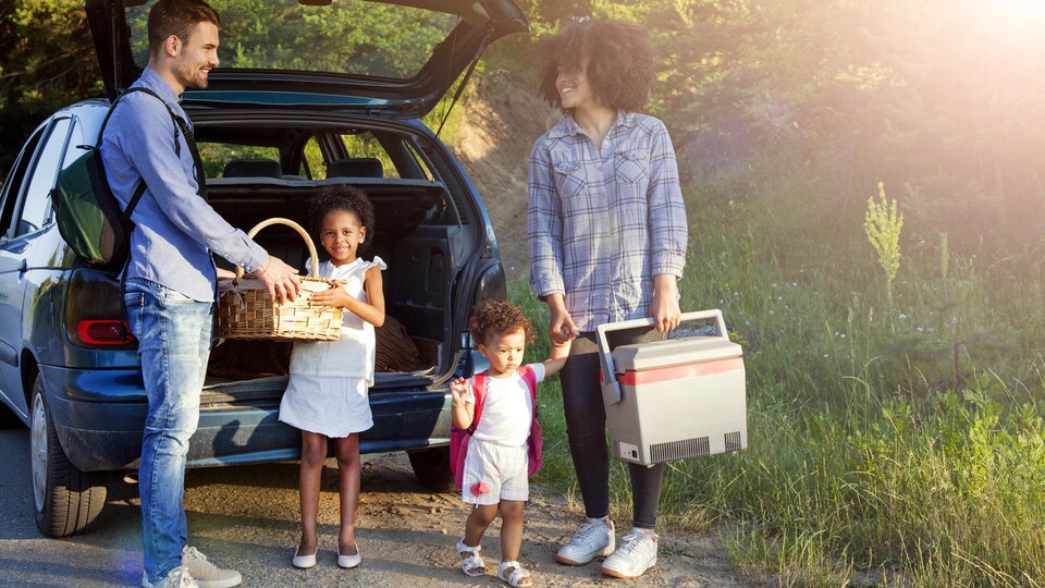 Une famille sort des paniers à pique-nique de son auto.