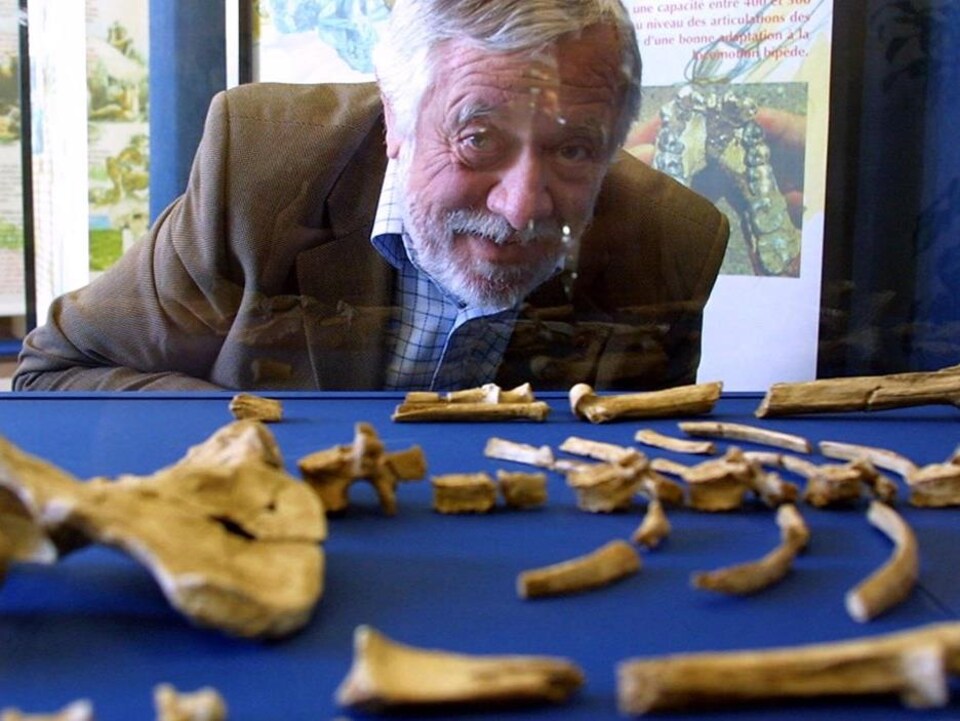 Le paléontologue Yves Coppens pose derrière une vitrine sous laquelle sont exposés des ossements de Lucy.