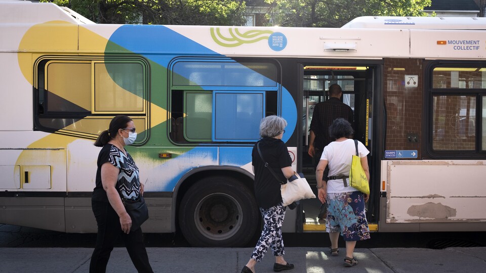 Des personnes entrent par la porte arrière d'un autobus de la STM.