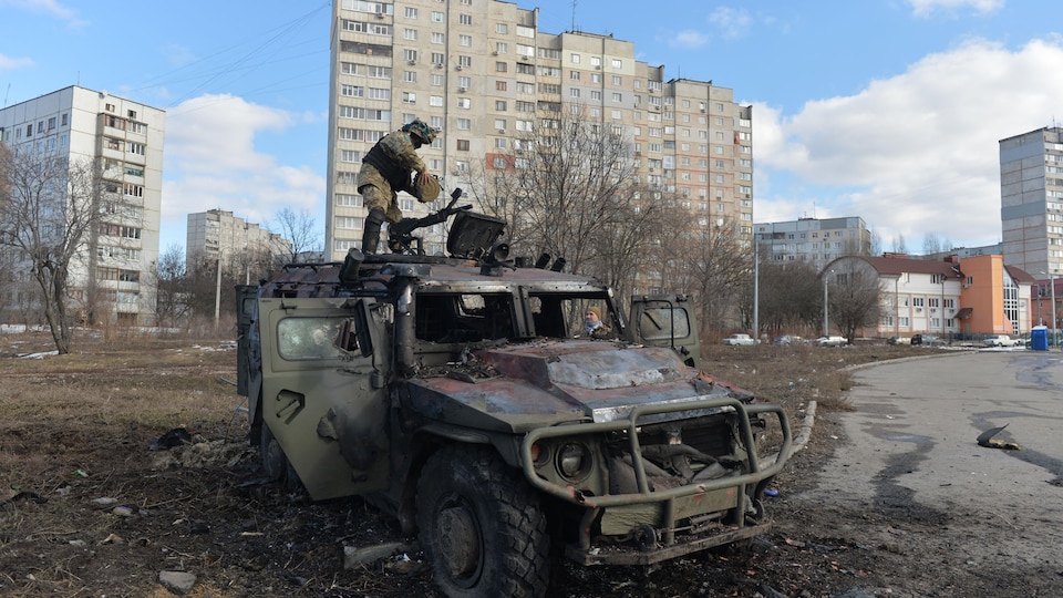 Un combattant de la Défense territoriale ukrainienne examine un véhicule.