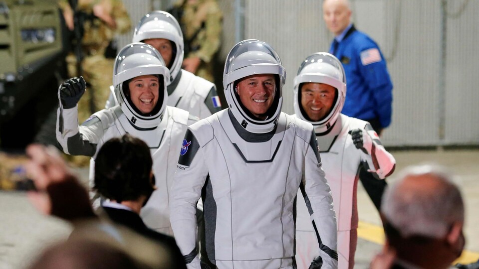 Les quatre astronautes fébriles et souriants; deux d'entre eux lèvent le poing.
