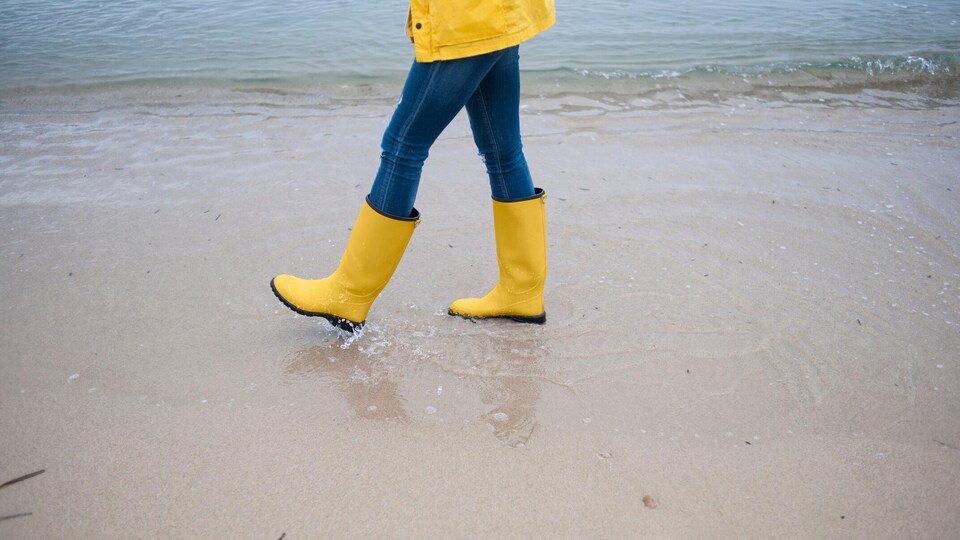 Une personne marche sur le bord de l'eau.