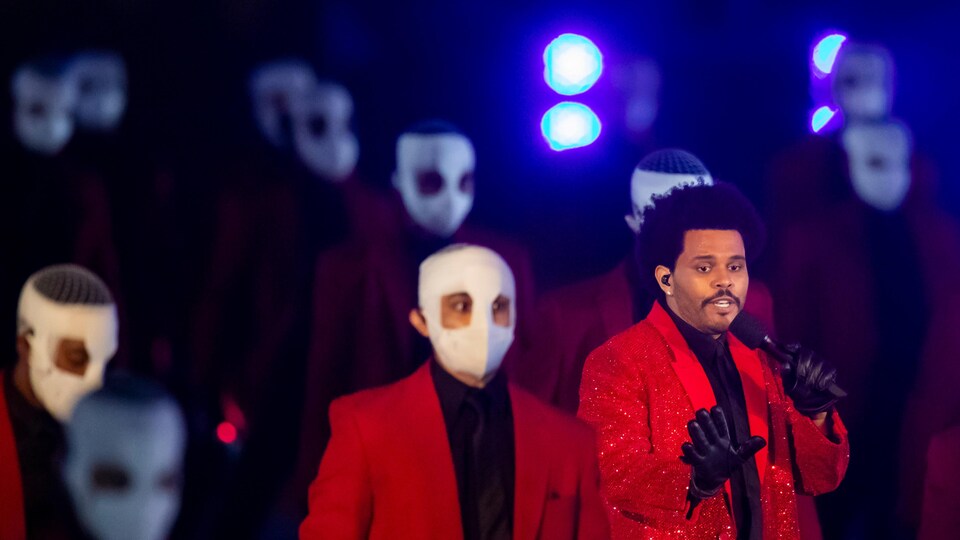 The Weekend chante sur scène avec des danseurs masqués.