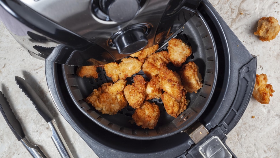 Des croquettes de poulet se trouvent dans le panier d'une friteuse à air. 