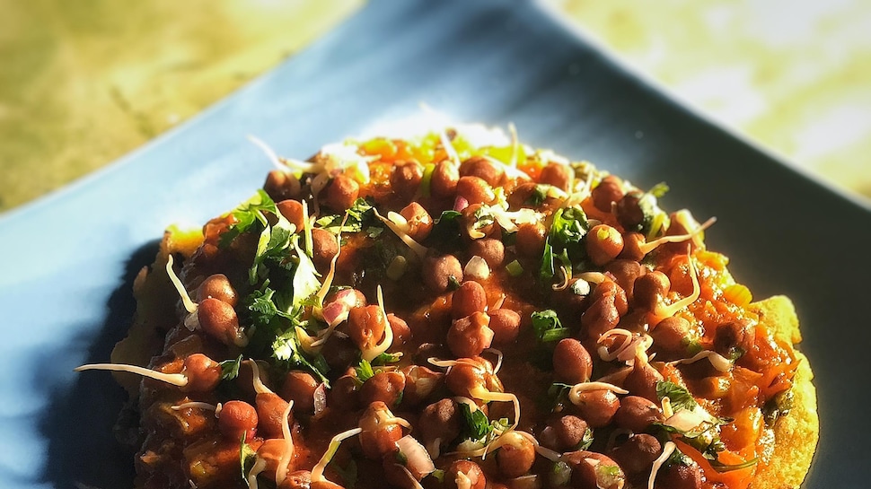 Un plat coloré de pois chiches dans une assiette bleue sur une table en bois. 