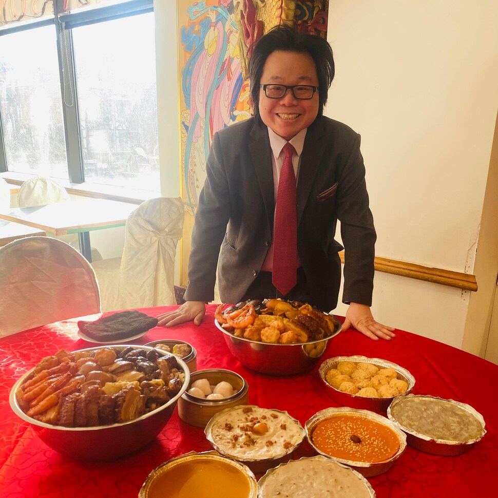 Winston Chan se tient à une table entouré de plats traditionnels. 