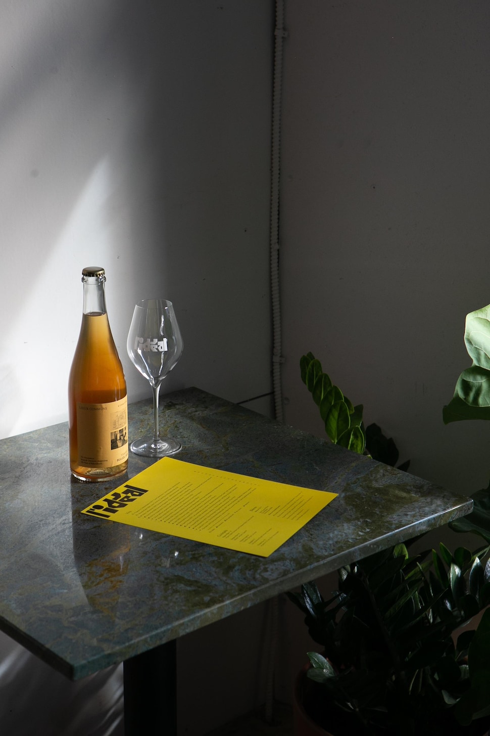 Un menu, une bouteille et un verre de vin sont posés sur une table. 