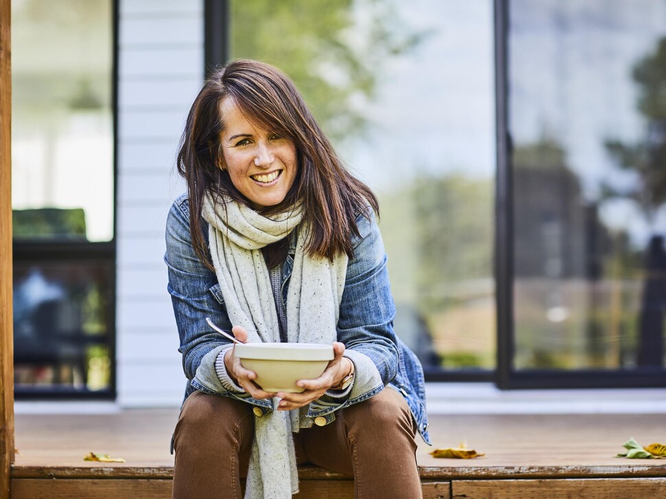 Geneviève O'Gleman assise sur une terrasse, un bol entre les mains