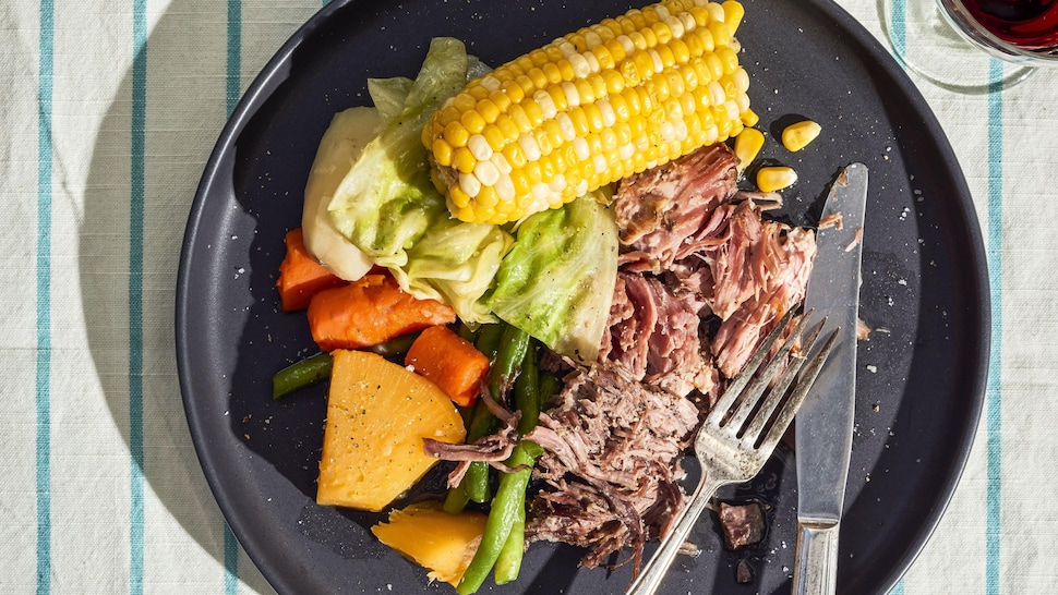 Une assiette noire remplie de légumes et de viande.