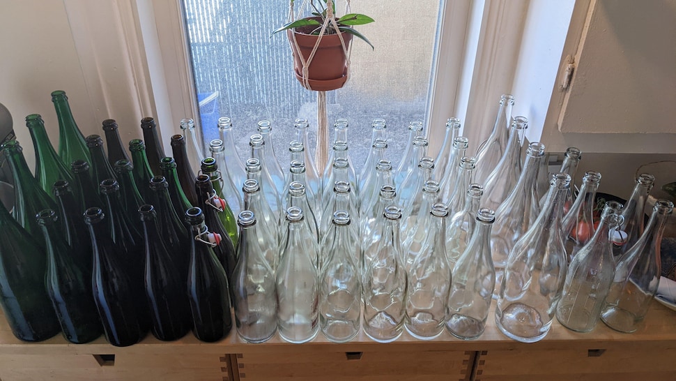 Plusieurs dizaines de bouteilles vides et propres sur un comptoir.