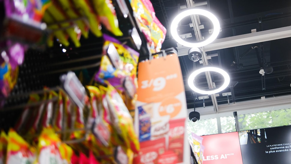 Un étalage de produit dans un dépanneur. Au plafond, des lumières vives et des caméras de surveillance.