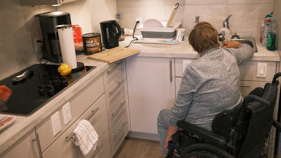 Une personne en fauteuil utilise l'évier d'une cuisine.