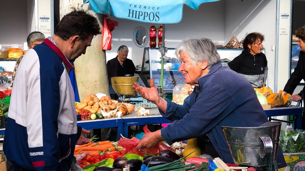 Femme qui vend des légumes dans un marché croate.