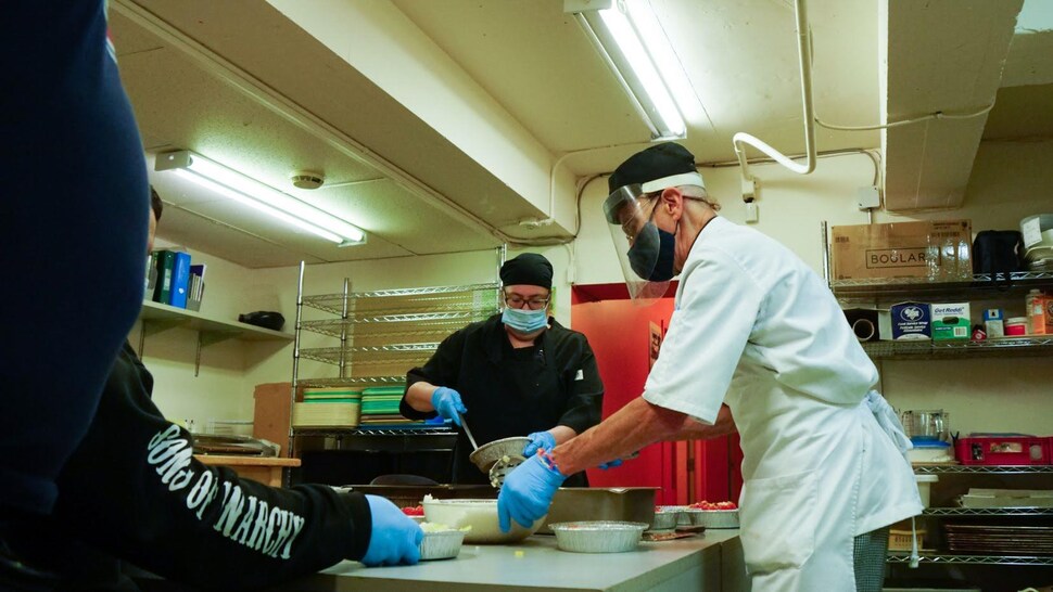 Paul Bergeron cuisine en compagnie d'autres personnes.