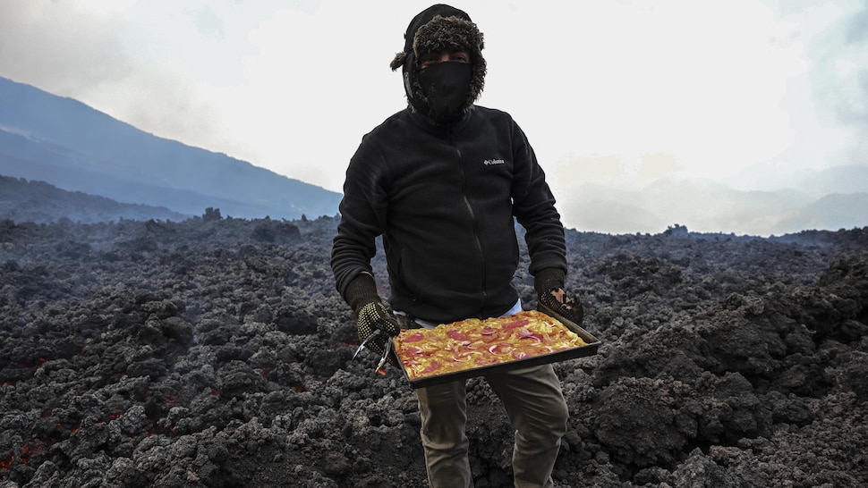 Un homme tient une pizza cuite sur la lave d'un volcan.