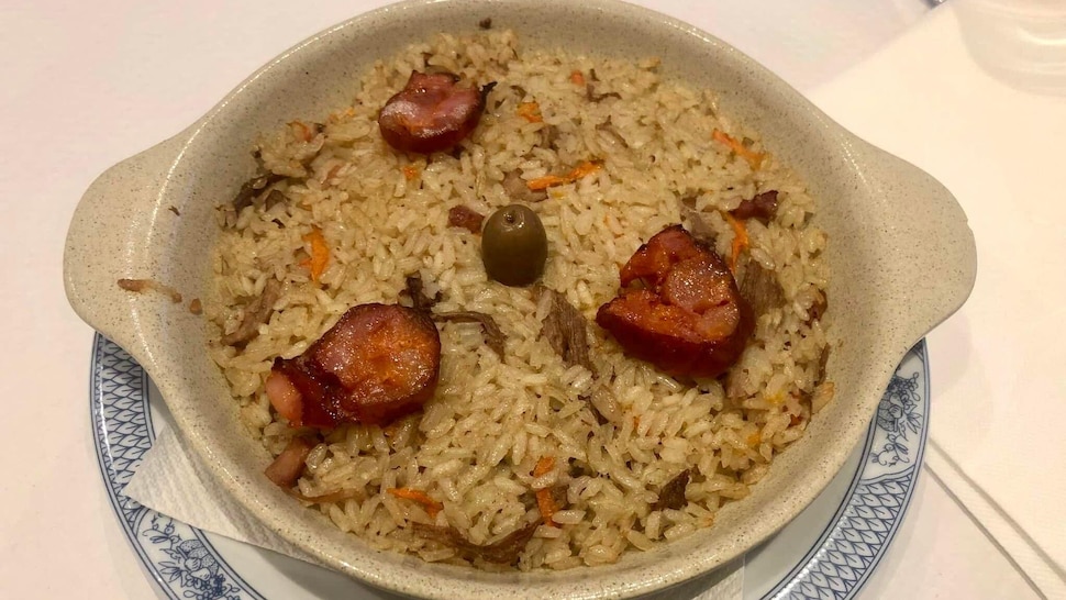 Un plat de riz au canard avec trois morceaux de chorizo et une olive. 