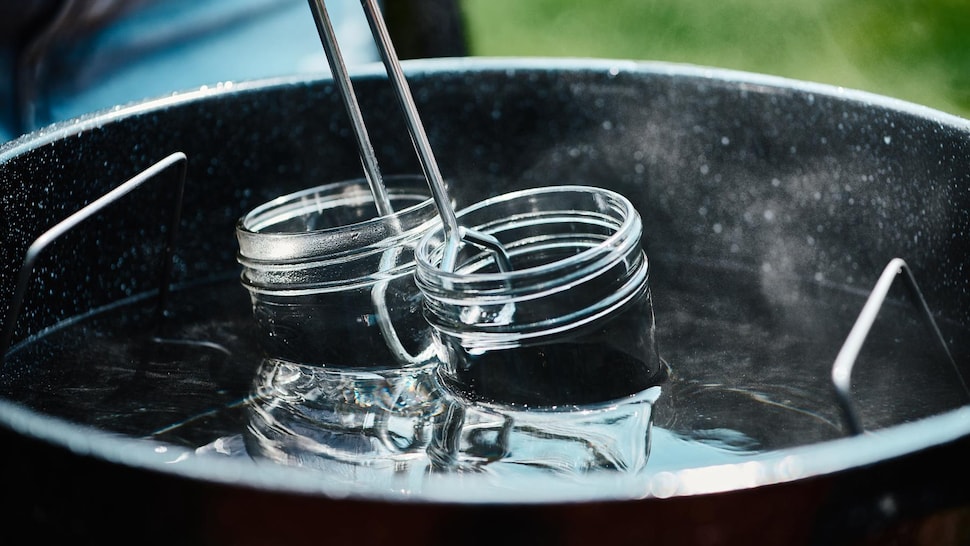Deux pots de conserve en verre dans une marmite remplie d'eau.